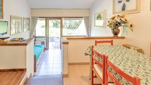 A cozy room with a dining table, chairs, a TV, and a window with curtains. - Beachside Holiday Home in Punta Ala (Castiglione della Pescaia)