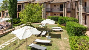 A courtyard with lounge chairs, umbrellas, and a tree. - Holiday Home in Collazone With Pool & Sauna (Collazzone)
