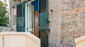 Un edificio con contraventanas verdes, una puerta de madera y un muro de ladrillo.