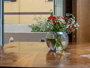 Eine transparente Glasvase mit Blumen auf einem Holztisch.