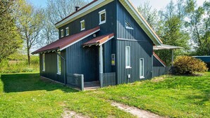 Una casa de dos pisos con fachada azul oscuro, techo rojo y un pequeño porche delantero.