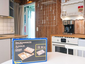 A kitchen with wooden cabinets, a coffee machine, and a chessboard on the counter. - 5 Person Holiday Home in Hovborg (Hovborg)
