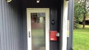 Una puerta con un panel de vidrio, un buzón y un apartado de correos en la pared.