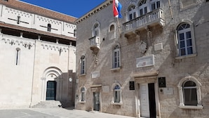 A historic building with a stone facade, multiple windows, and a flag.