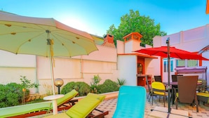 A pool area with lounge chairs, a pool, and umbrellas.