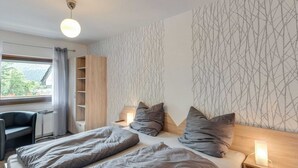 Un dormitorio con cama, mesitas de noche, escritorio y silla.