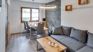 Una sala moderna con un sofá gris, una mesa de centro de madera y un comedor con mesa y sillas.