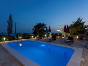 A swimming pool with lounge chairs and umbrellas, surrounded by a fence and trees. - Gorgeous Villa in Tučepi with Private Swimming Pool  (Tucepi)