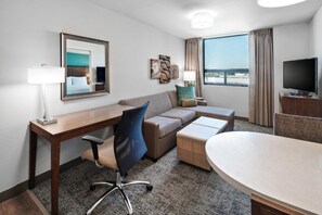 A hotel room with a desk, a sofa, a TV, and a large window. - Staybridge Suites Irvine - John Wayne Airport IHG (Costa Mesa)