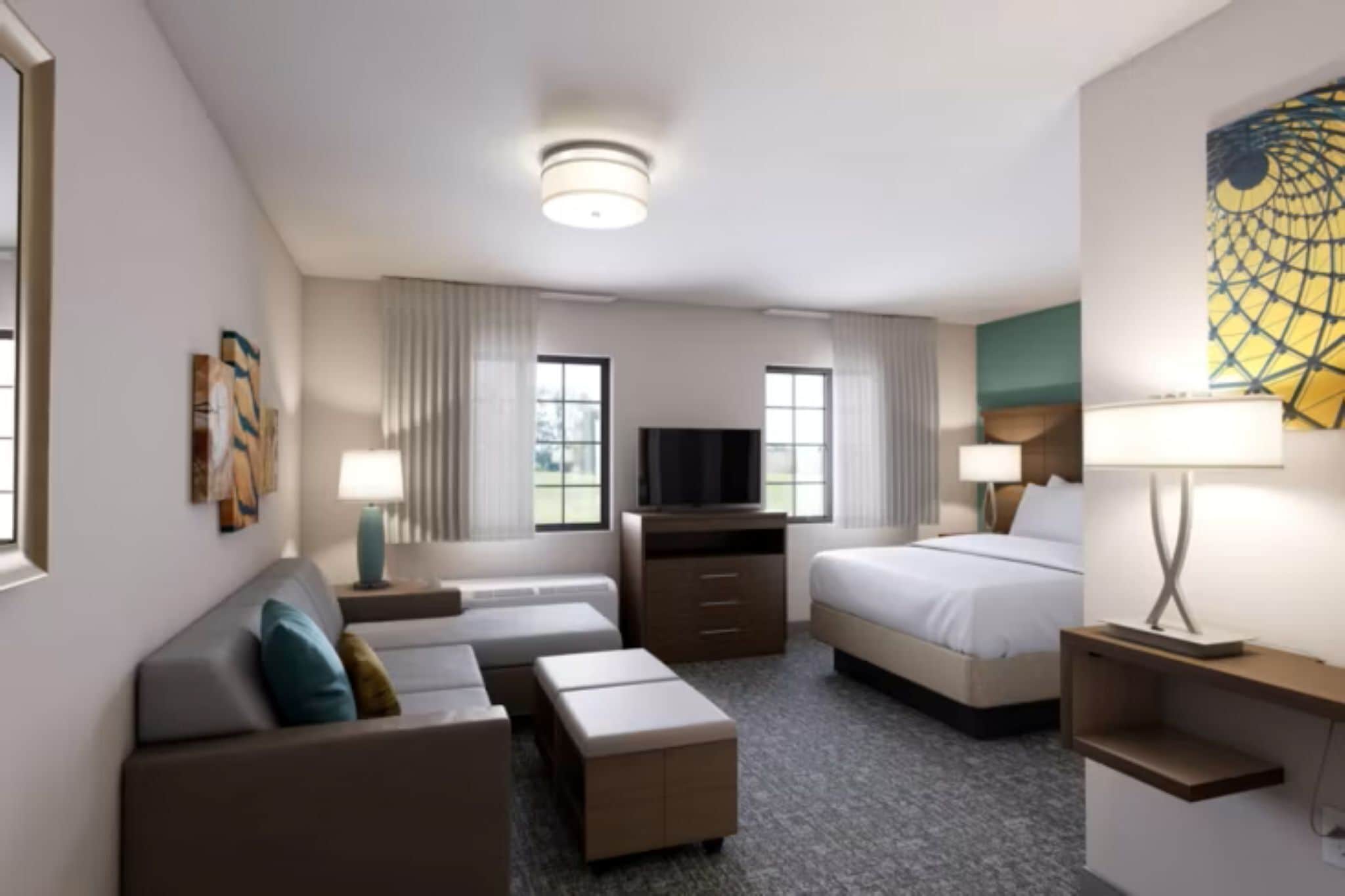 Ein modernes Hotelzimmer mit Sofa, Bett, Fernseher und Schreibtisch.