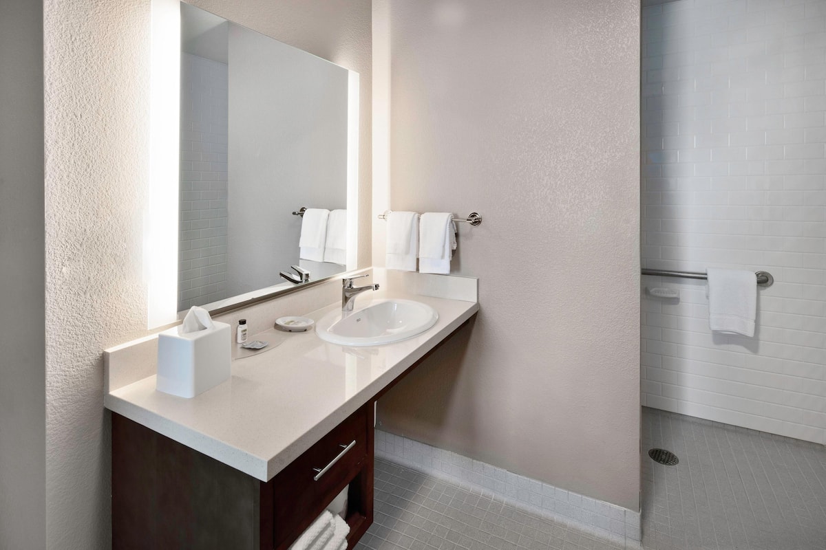 A modern bathroom with two sinks, a large mirror, and a shower area.