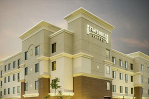 Edificio del hotel Staybridge Suites con fachada simétrica, múltiples ventanas y señalización destacada.
