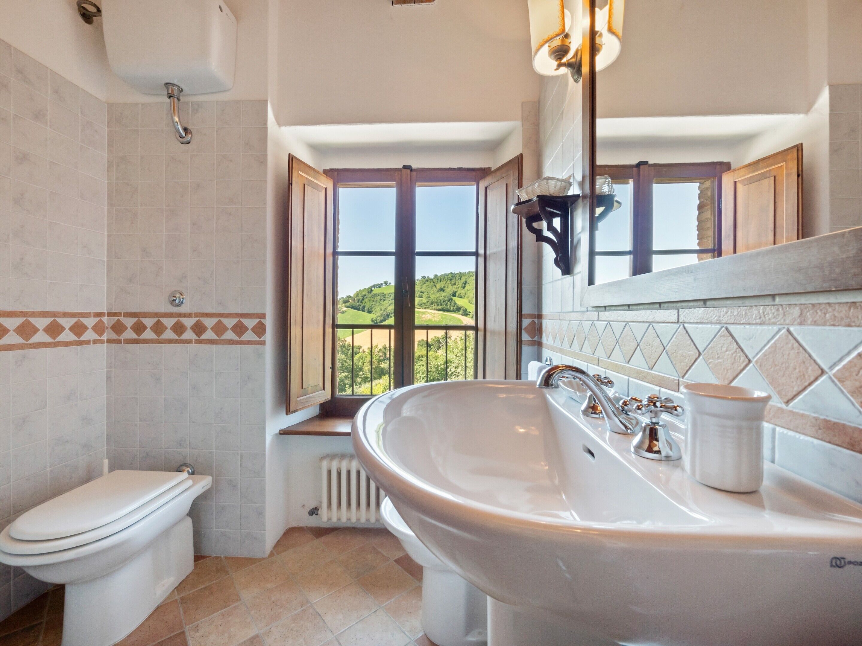 Une salle de bain avec une grande fenêtre, une baignoire et des toilettes.