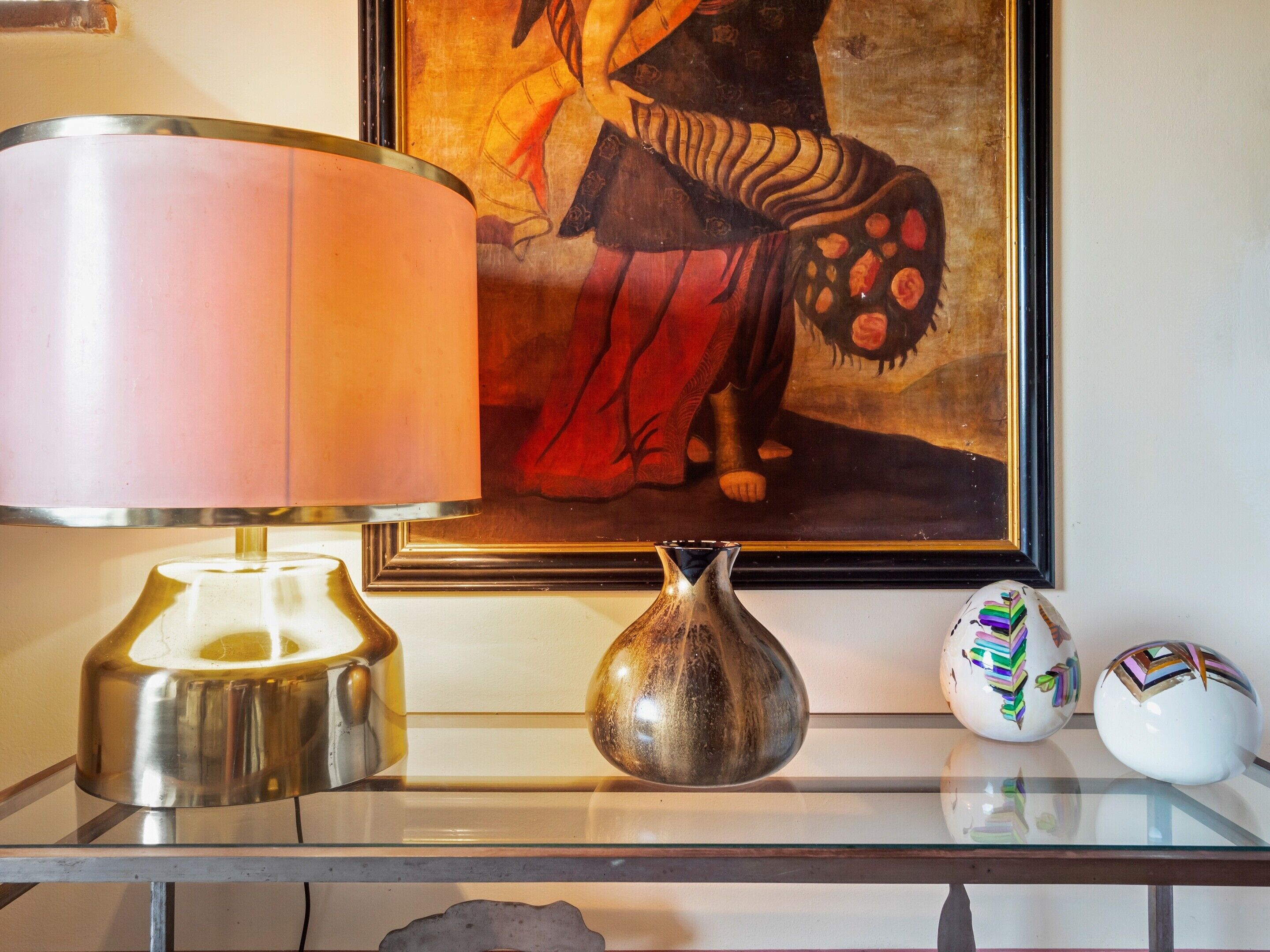 A table with a lamp, a vase, and two decorative items.
