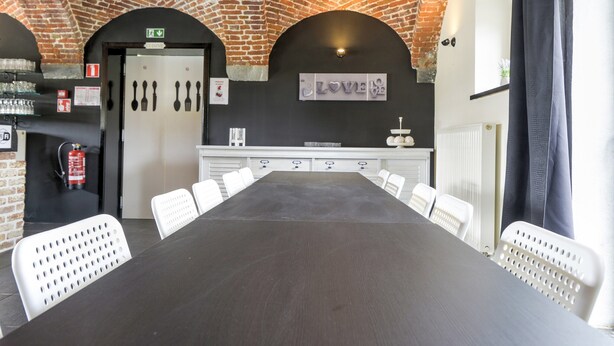 A conference room with a long table and white chairs, brick walls, and a 'LOVE' sign on the wall. - Grand Family Holiday Home in Houyet (Houyet)