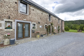 A brick building with a gravel driveway, a door, and flower planters. - Grand Family Holiday Home in Houyet (Houyet)