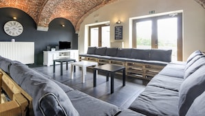 A modern lounge with a brick ceiling, a large clock, and a seating area with sofas and tables. - Grand Family Holiday Home in Houyet (Houyet)