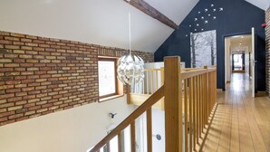 A spacious loft with exposed wooden beams, a brick wall, and a wooden floor. - Grand Family Holiday Home in Houyet (Houyet)