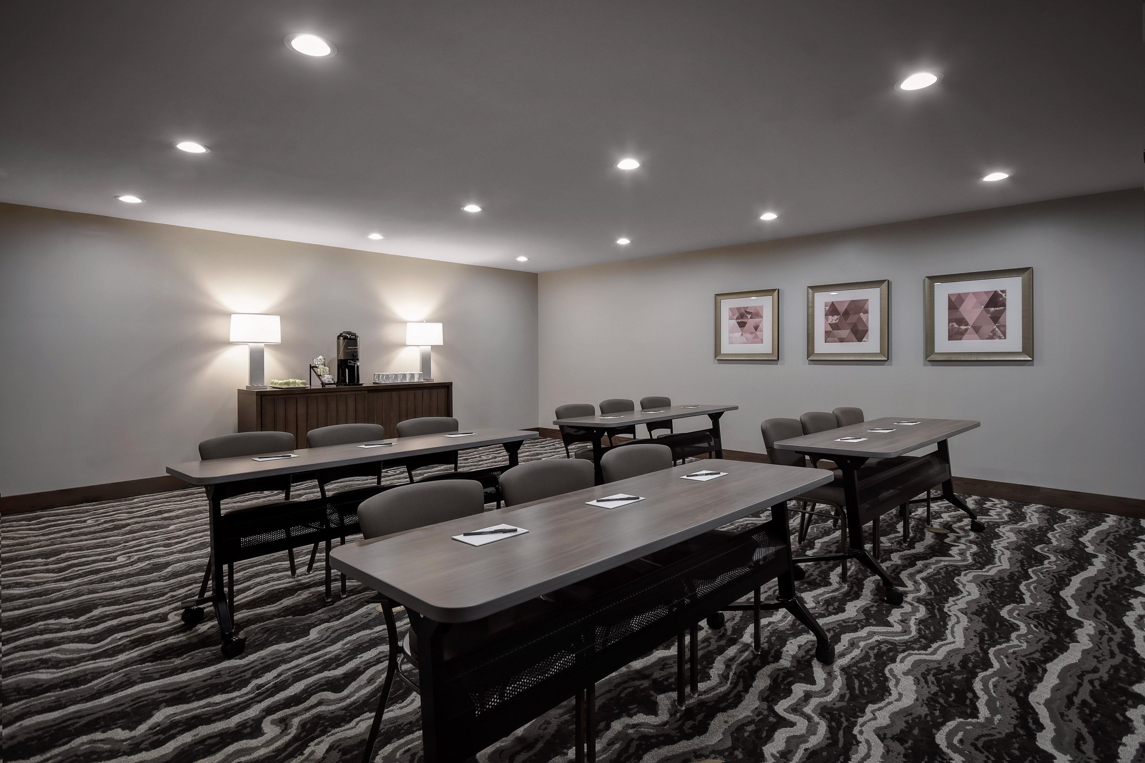 A conference room with multiple tables and chairs, a reception desk, and framed artwork on the wall.