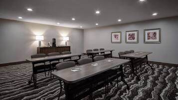 A conference room with multiple tables and chairs, a reception desk, and framed artwork on the wall.