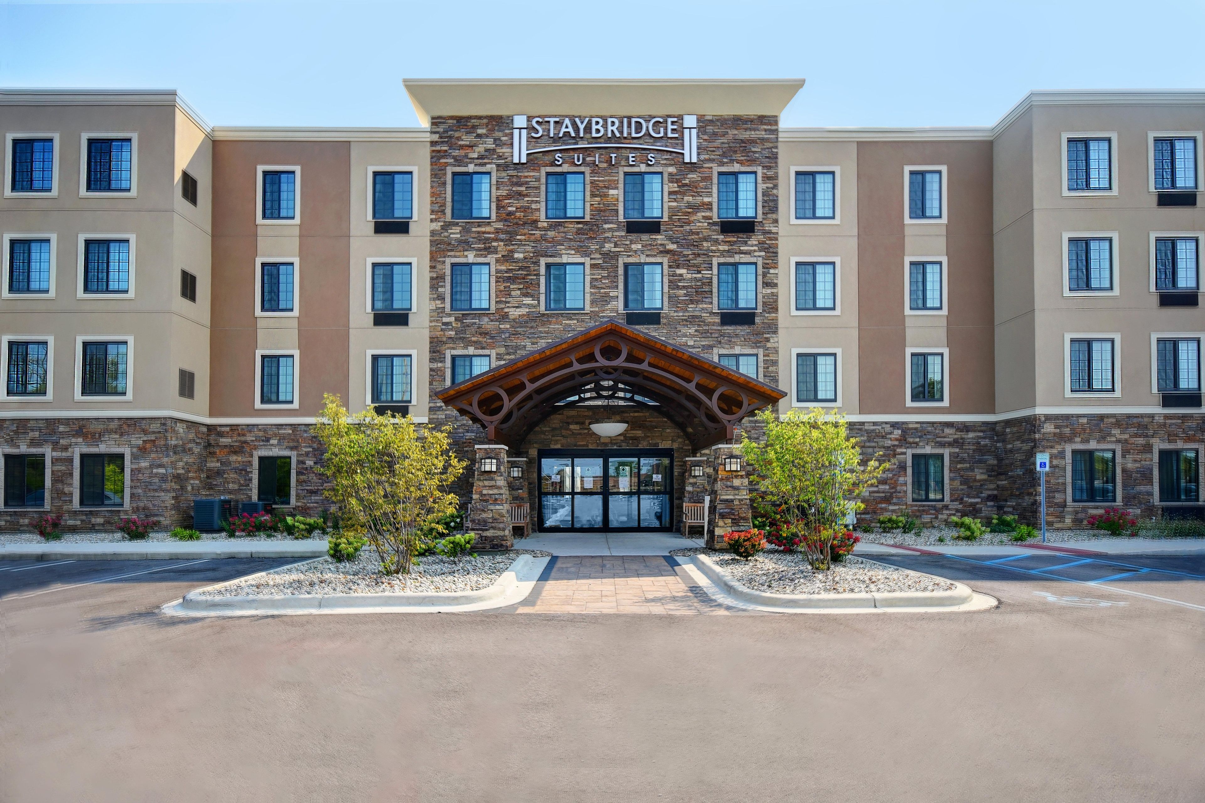 Entrada d'un hotel Staybridge Suites amb façana de pedra, diverses finestres i una arcada central.