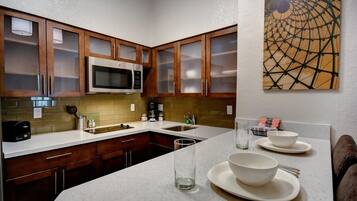A kitchen with wooden cabinets, a microwave, a coffee maker, and a sink.