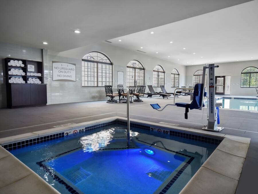 Uma área de piscina interior moderna com uma placa visível indicando "SEM SALVAVIDAS EM FUNCIONAMENTO, MERGULHO PROIBIDO".