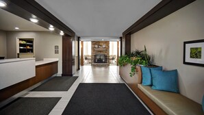 A hotel lobby with a reception desk, a seating area with cushions, a fireplace, and a plant. - Staybridge Suites Holland (Holland)