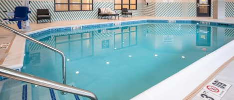 A swimming pool with a pool lift, a no diving sign, and a maximum number of bathers sign.