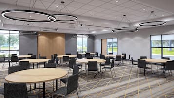 A conference room with round tables, black chairs, and modern pendant lighting.