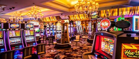 A casino floor with multiple slot machines and a chandelier.
