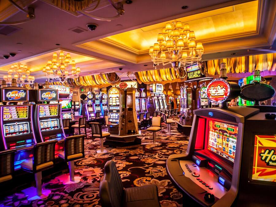 A casino floor with multiple slot machines and a chandelier.