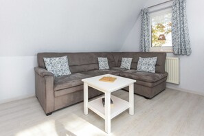A modern living room with a grey sectional sofa, a white coffee table, and patterned cushions.