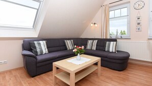 Una sala de estar moderna con un sofá modular gris oscuro, una mesa de centro de madera y un florero con flores.
