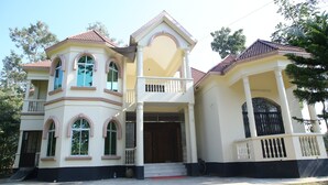 Une maison à deux étages dotée d’un balcon, de grandes fenêtres et d’une porte d’entrée.