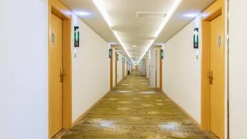 Un pasillo de hotel con puertas de madera, suelo alfombrado e iluminación en el techo.
