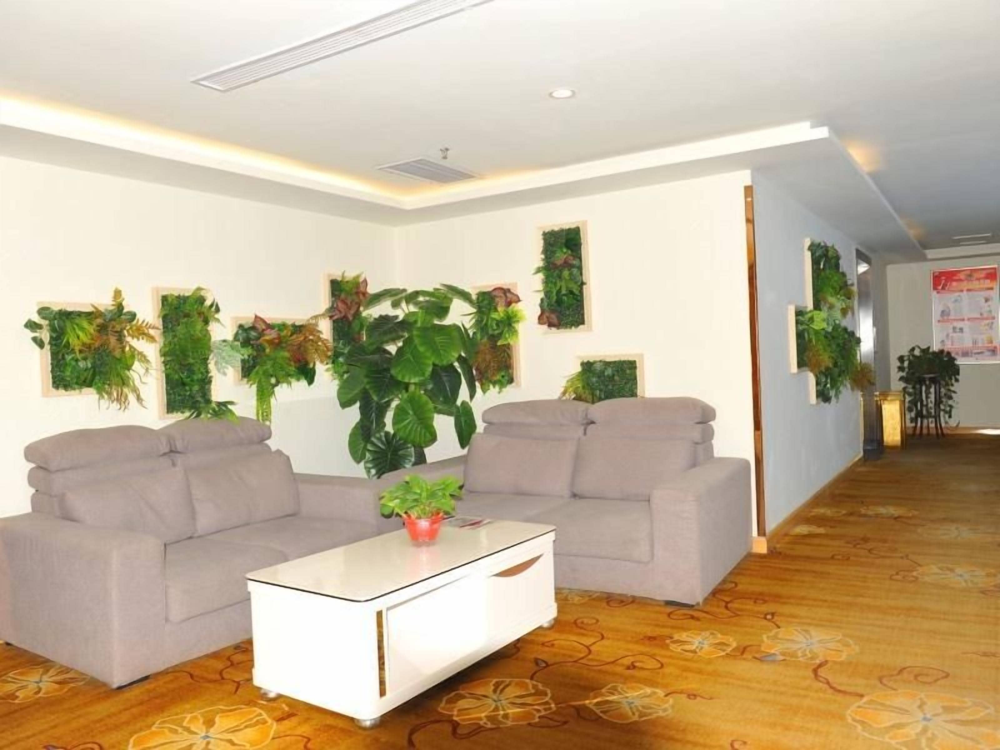 A modern living room with two sofas, a coffee table, and several wall-mounted plants.