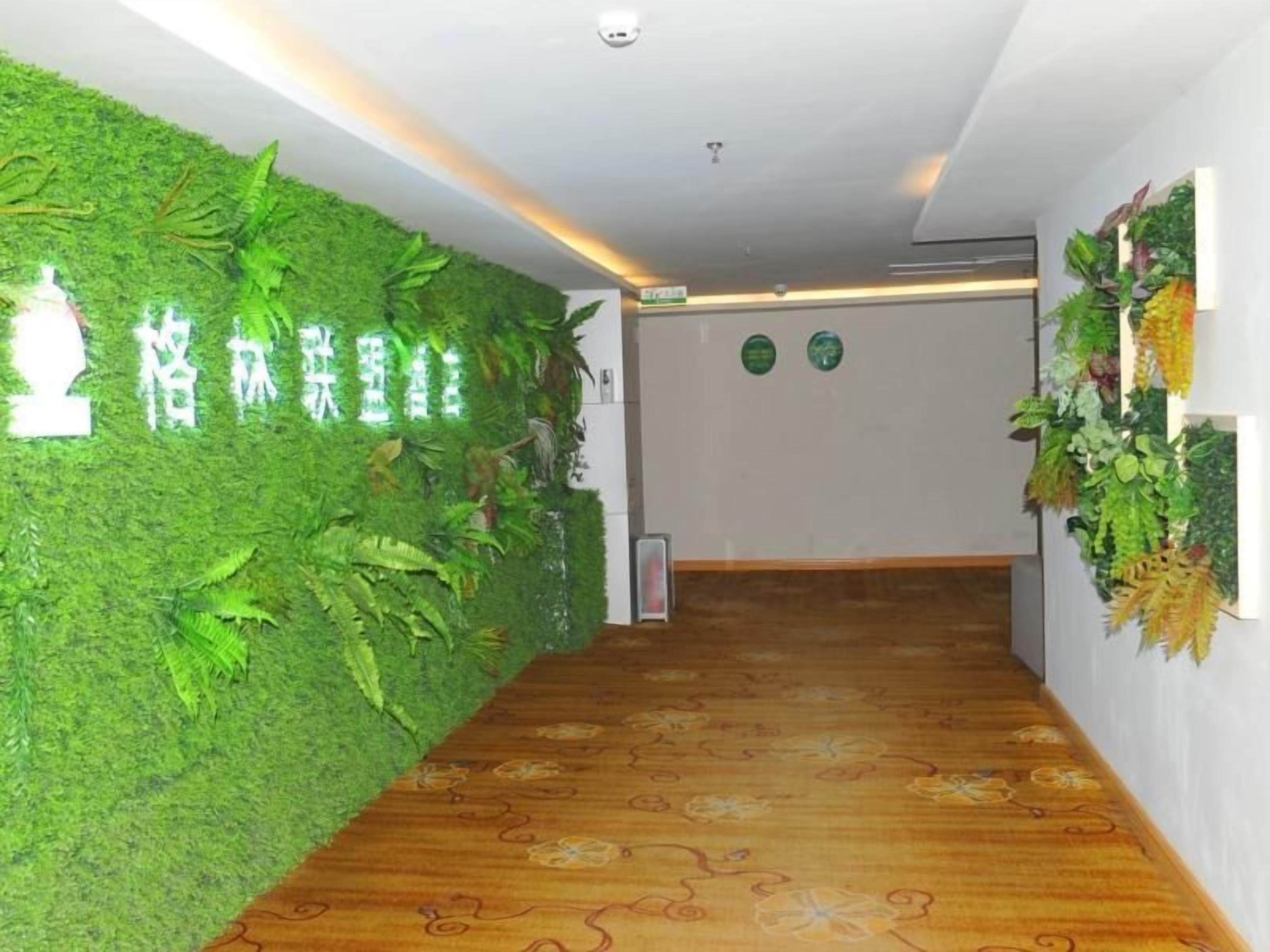 Pasillo con pared verde cubierta de follaje y piso de madera con estampado floral.