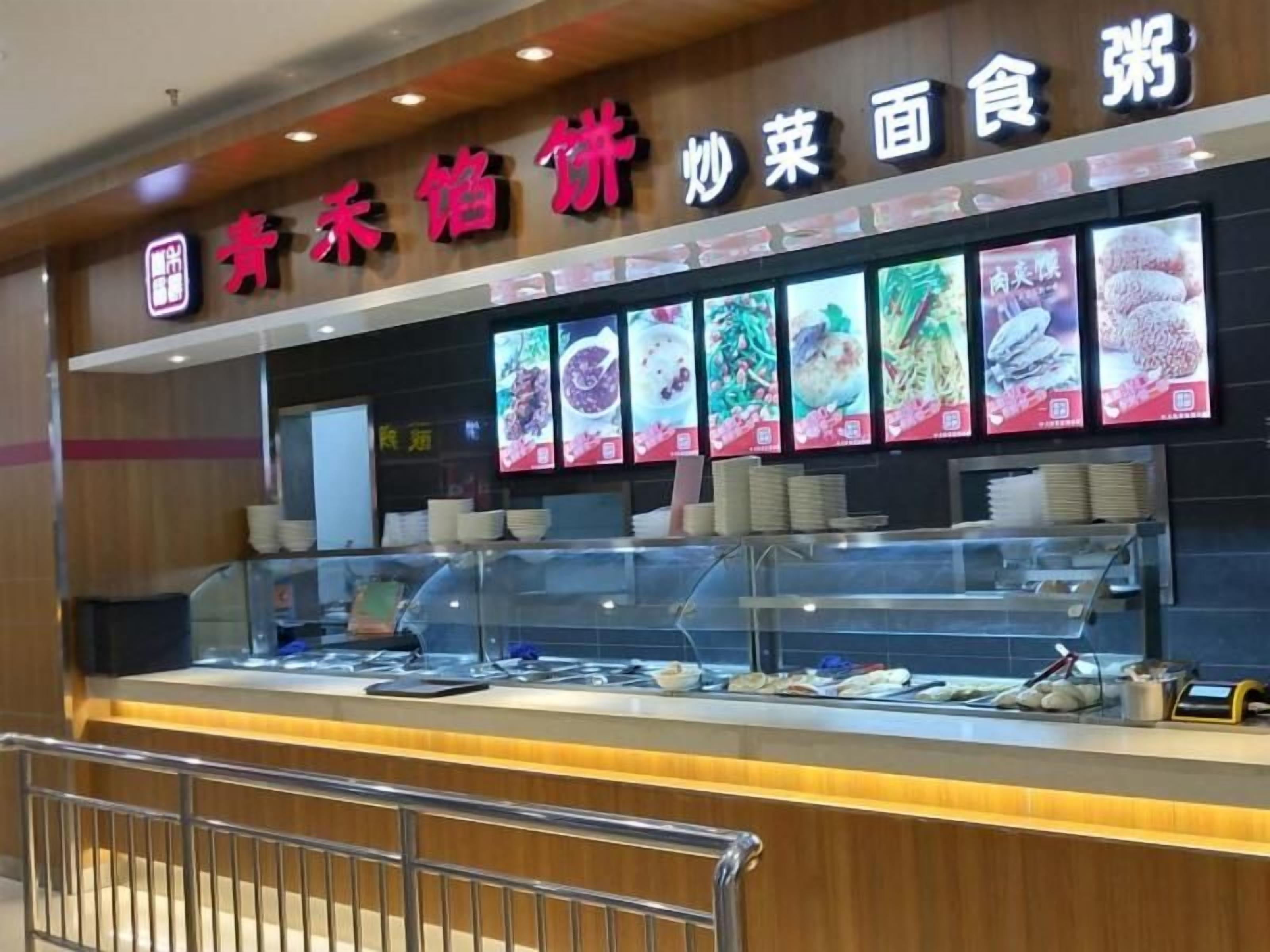 A food counter with various dishes displayed and a sign above indicating it is a buffet.