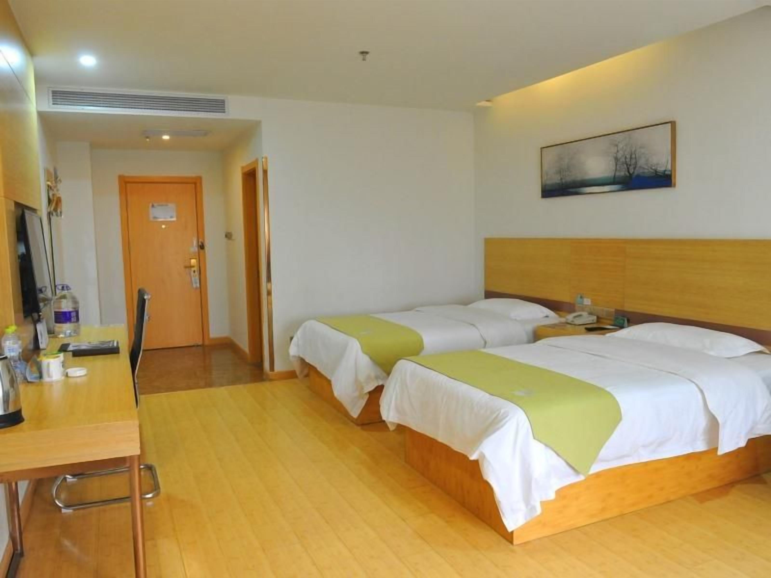 A hotel room with two beds, a desk, and a chair.
