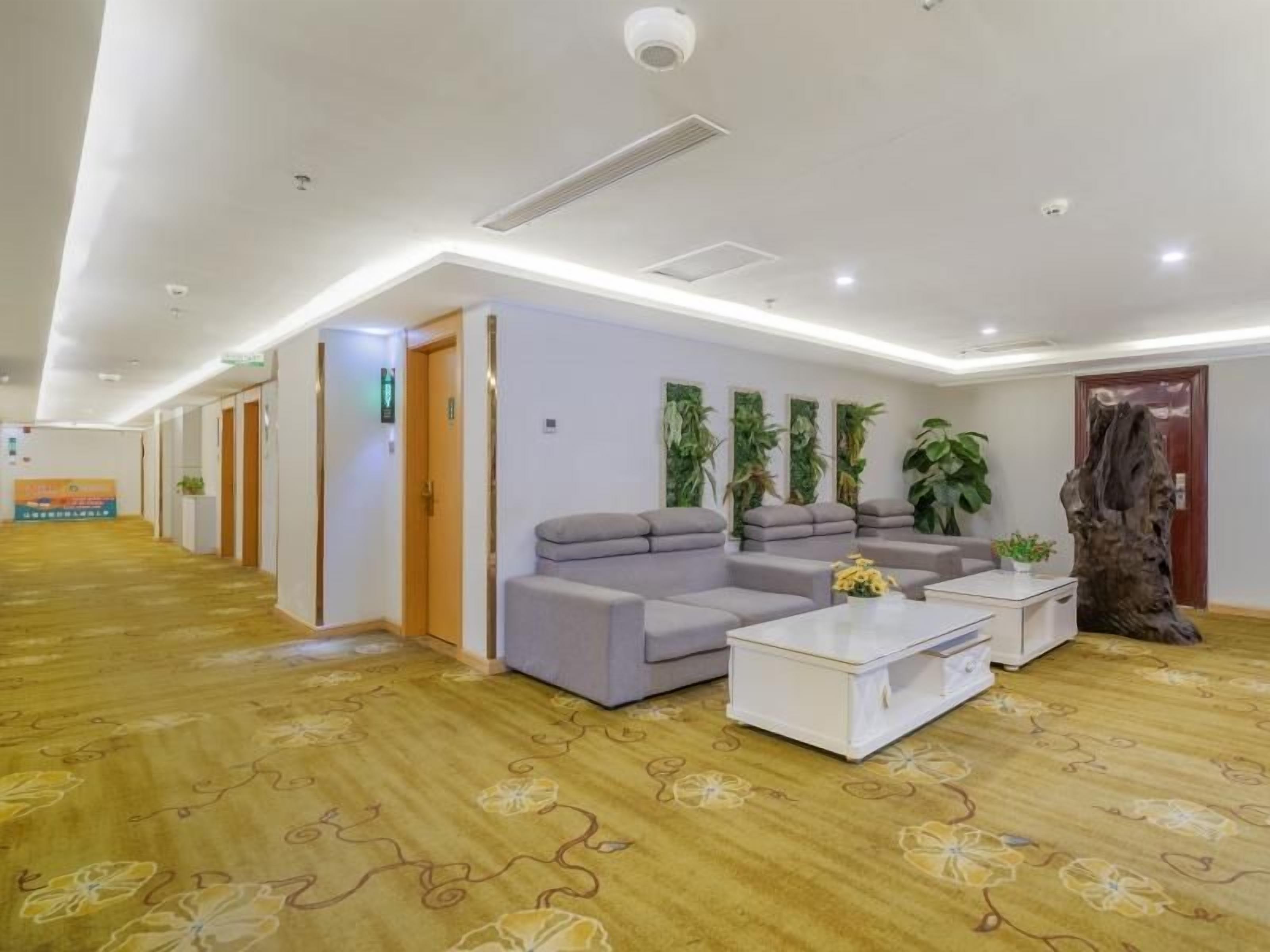 A hotel lobby with a reception desk, seating area, and a large wooden sculpture.