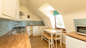 Une cuisine dotée d’un plan de travail en bois, de meubles blancs, d’un évier, d’une cuisinière et d’une fenêtre offrant une belle vue.