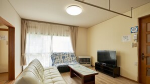 A living room with a sofa, a coffee table, a TV, and an air conditioner. - BBQ (千歳市白樺)