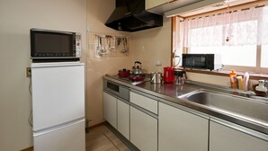 A compact kitchen with a microwave, stove, and sink. - BBQ (千歳市白樺)