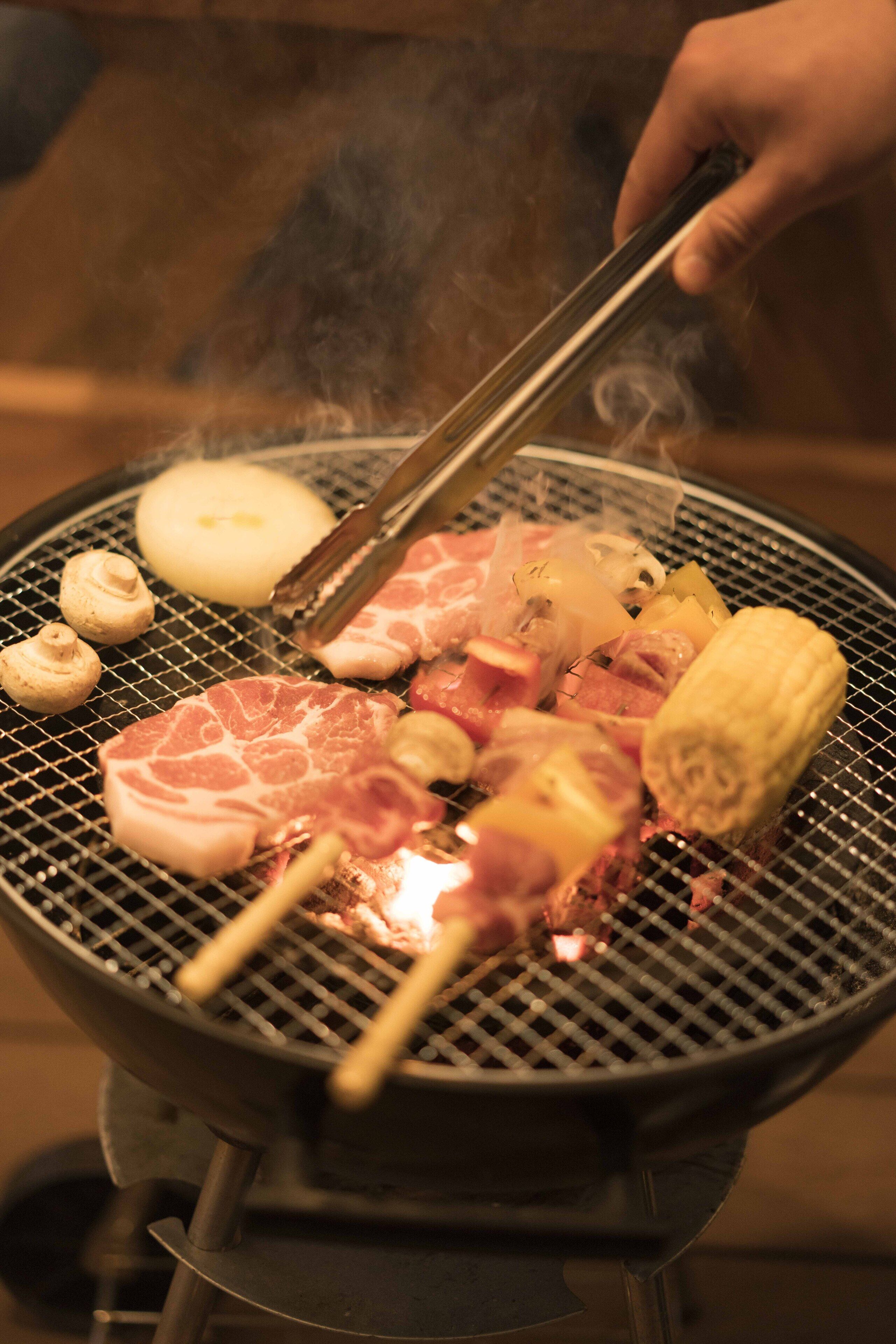 A grill with various meats and vegetables being cooked.