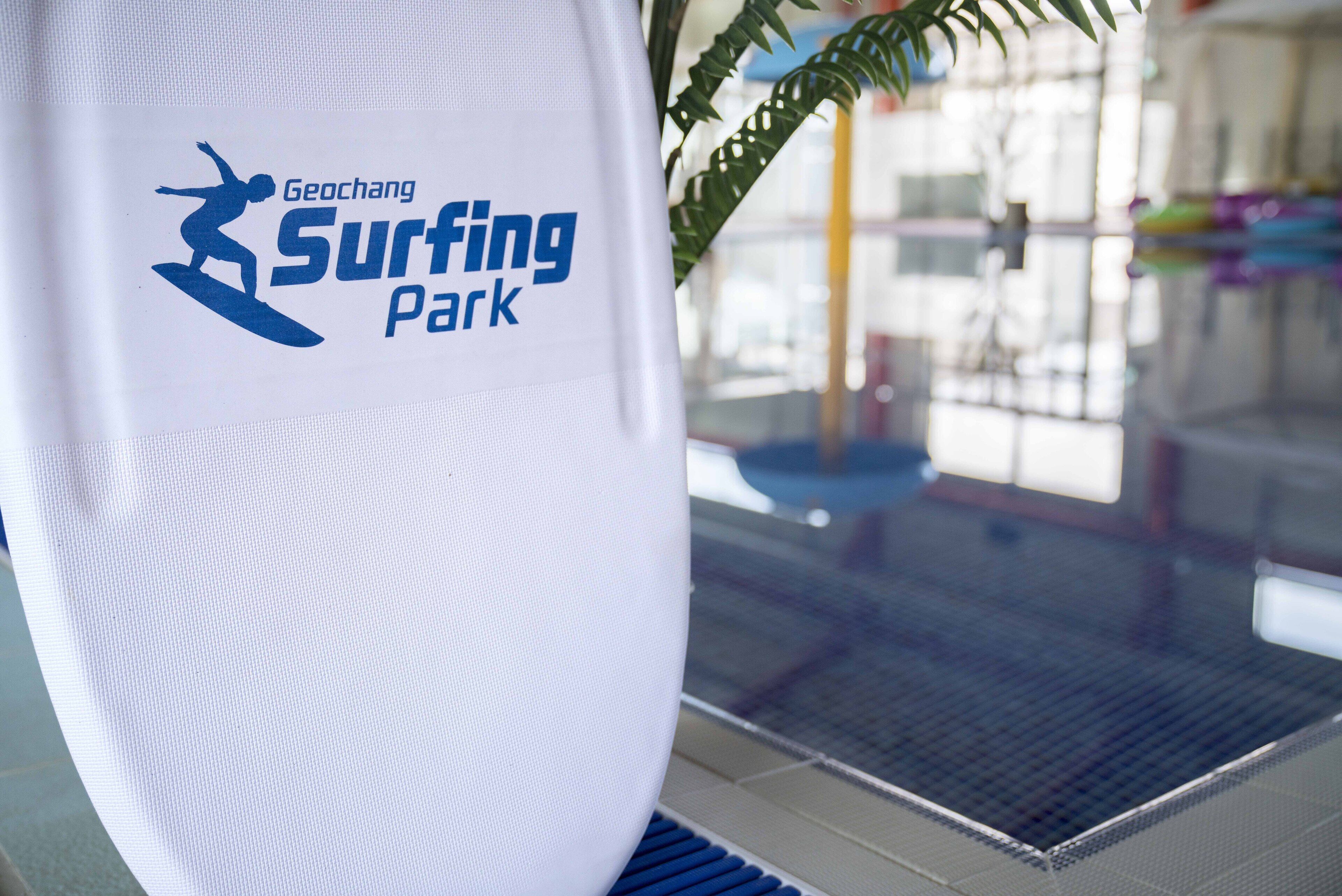 A white surfboard with the Geochang Surfing Park logo.