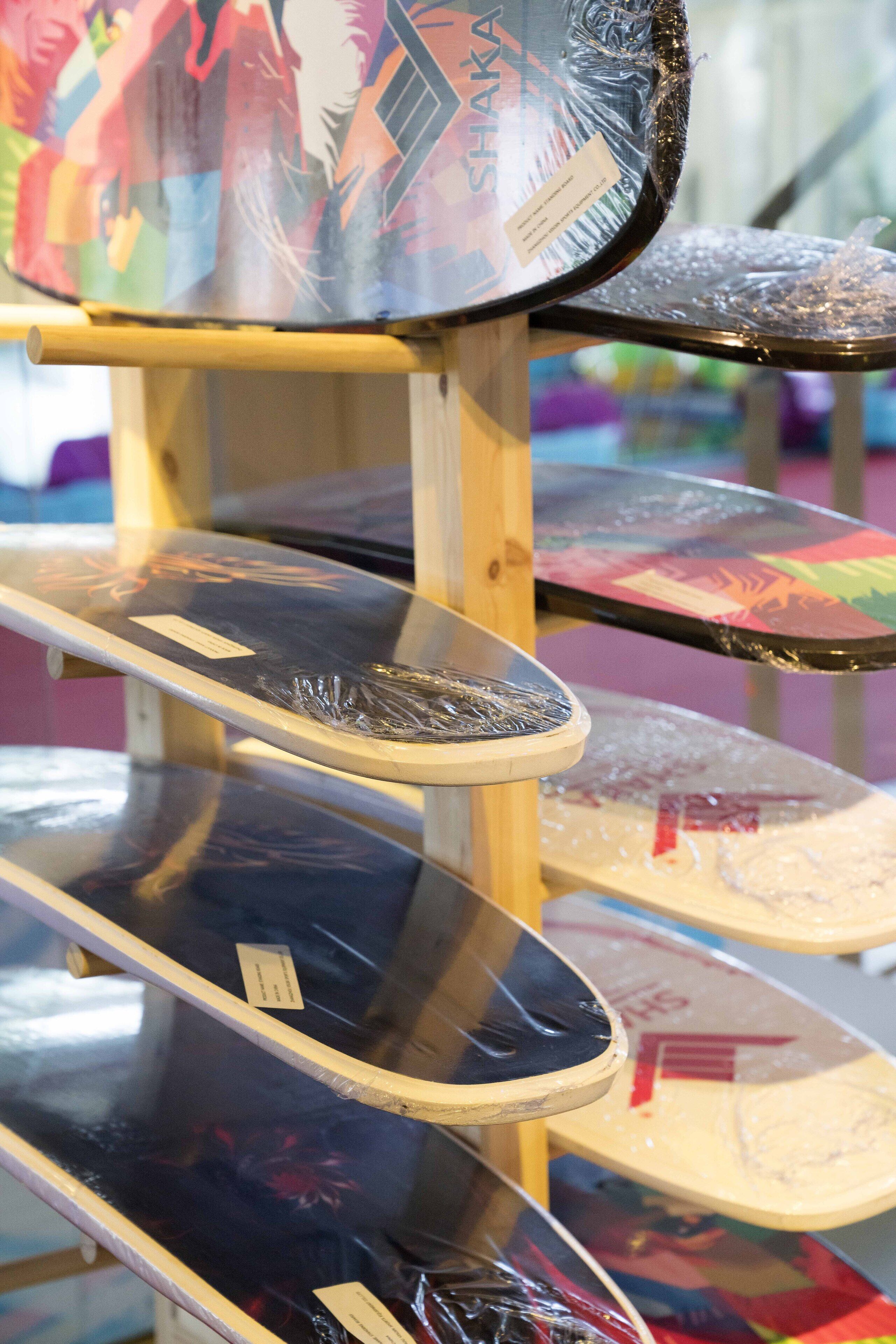 A display of skateboards with visible stickers and labels, arranged on a wooden stand.
