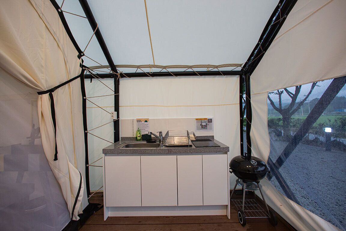 A compact kitchen with a sink, countertop, and a portable grill.