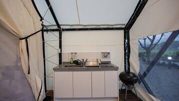 A compact kitchen with a sink, countertop, and a portable grill.