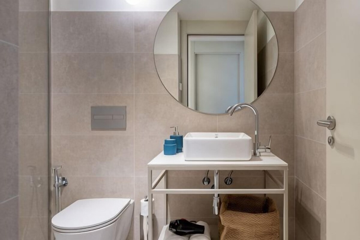 Ein Badezimmer mit Toilette, Waschbecken, Spiegel und Handtuchhalter.